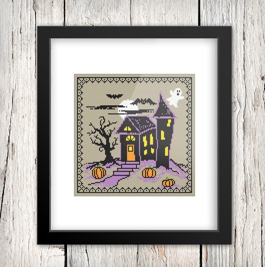 The image is a framed cross-stitch depicting a spooky Halloween scene with a castle, a ghost, and pumpkins.