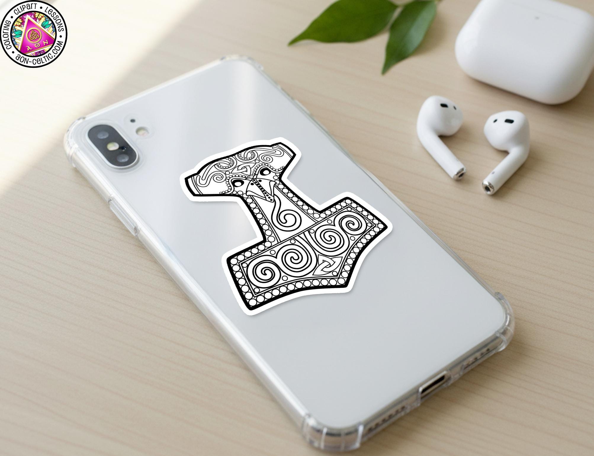 a smartphone with a decorative sticker of a hammer on its back cover, along with a pair of earbuds and a white earbud case on a wooden surface.