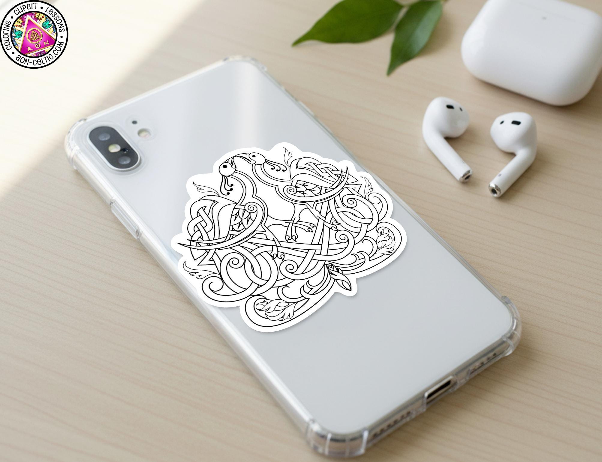 a smartphone with a sticker of a stylized bird design on its back cover, along with a pair of white earbuds and a white charging cable on a wooden surface.