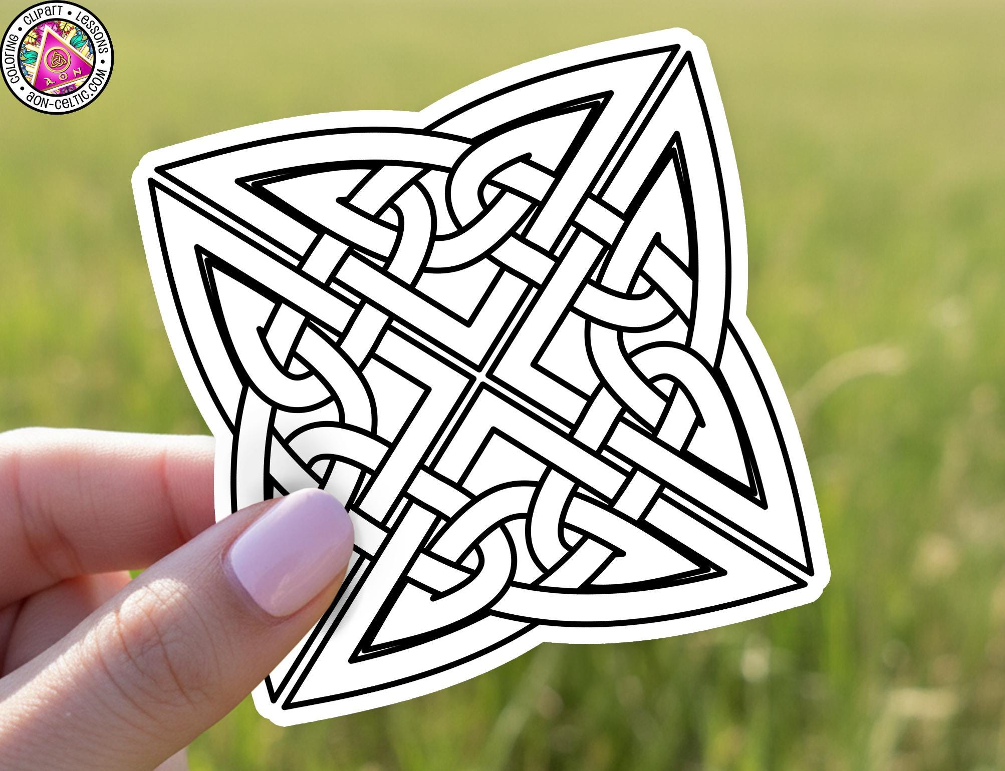 A hand holding a sticker with a geometric design featuring a symmetrical pattern of interlocking lines and shapes.
