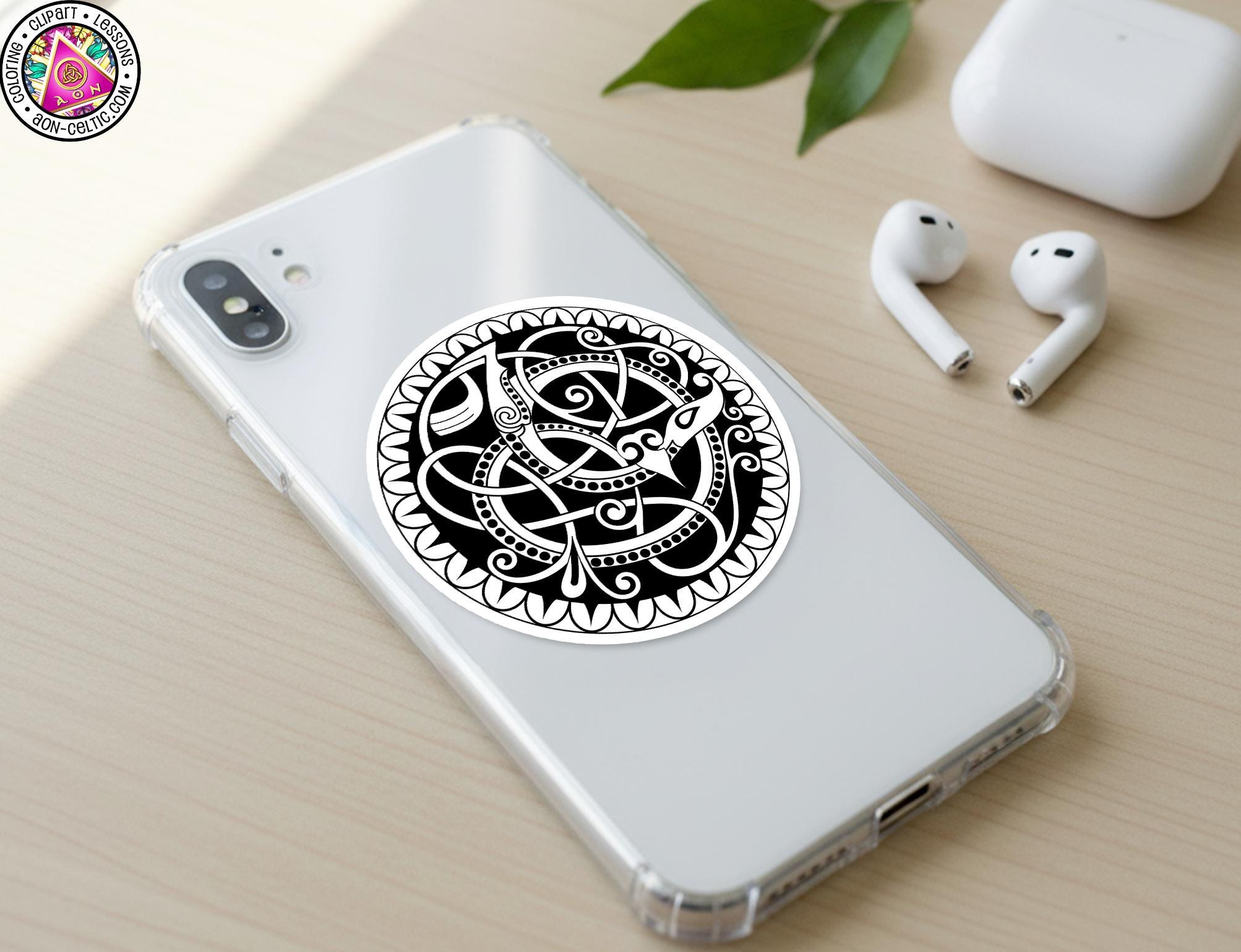 a smartphone with a decorative sticker on the back cover, along with a pair of earbuds and a white earbud case on a wooden surface.