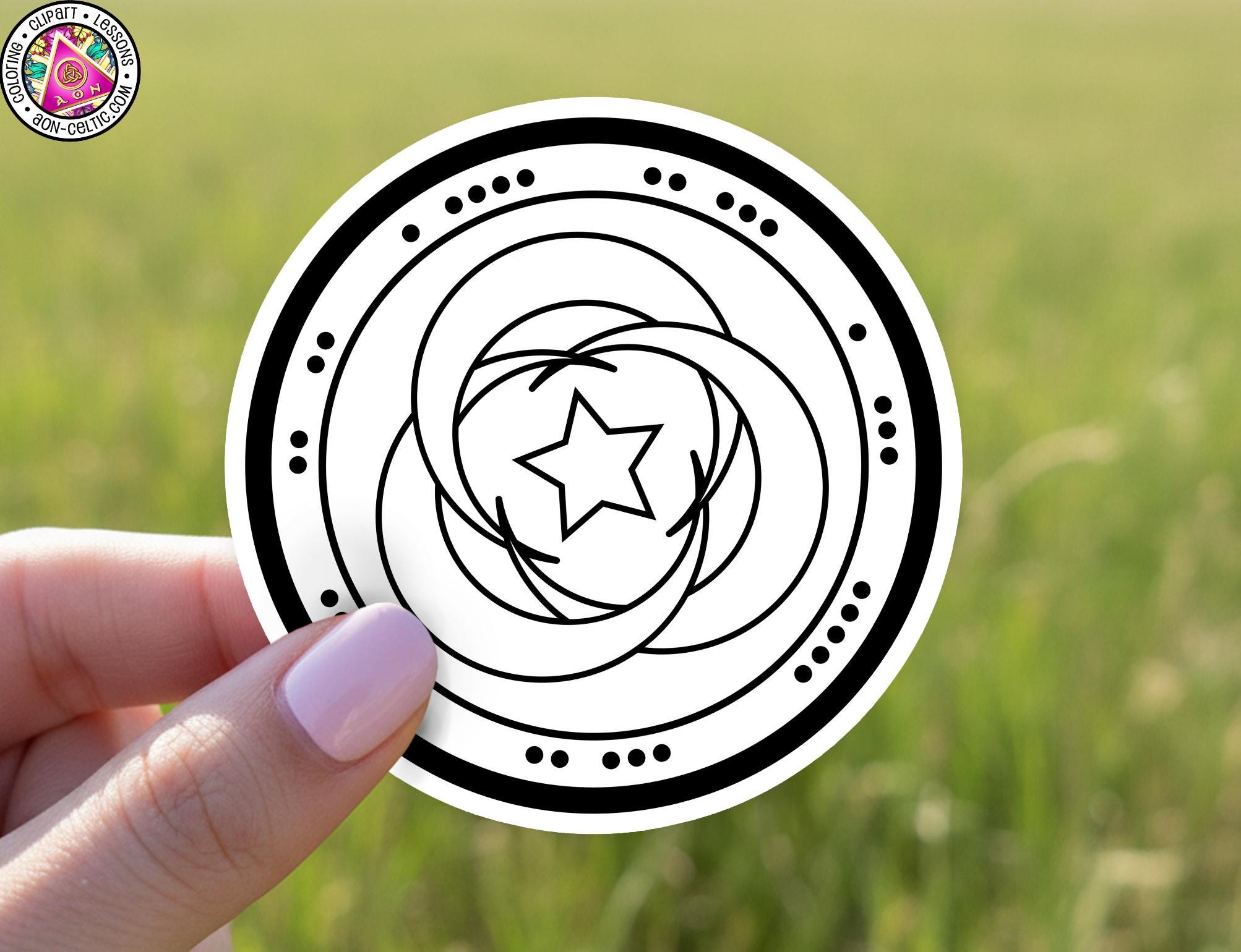 A hand holding a circular sticker with a black and white design featuring a star and concentric circles.