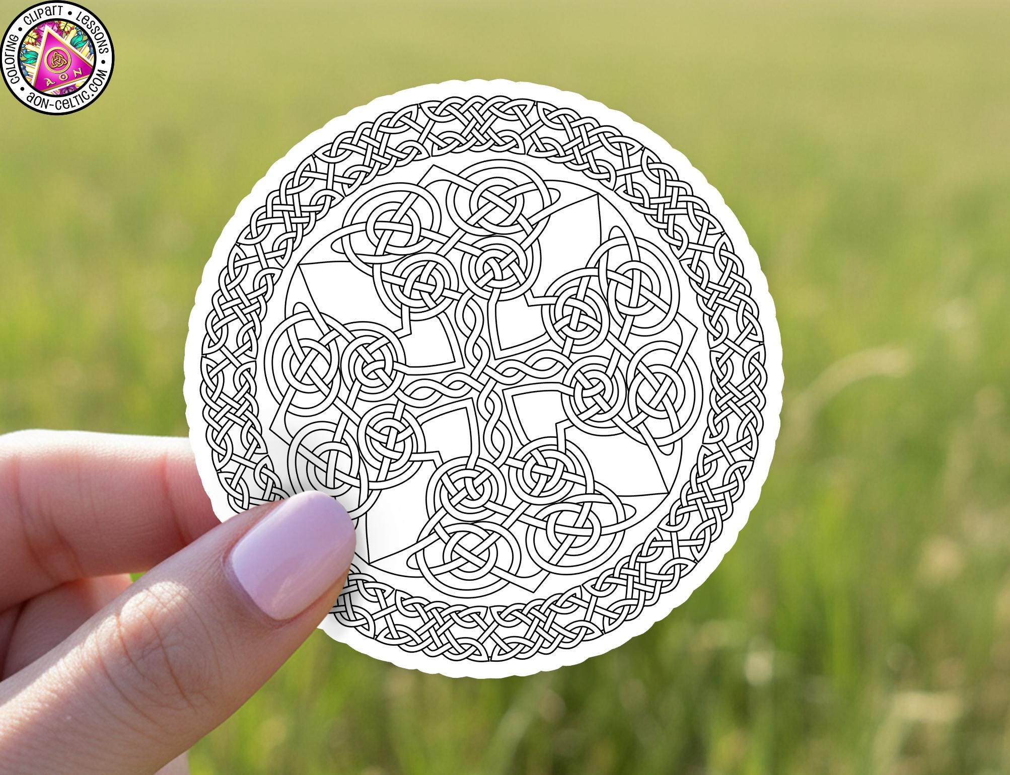 A hand holding a circular paper with intricate Celtic knot patterns.