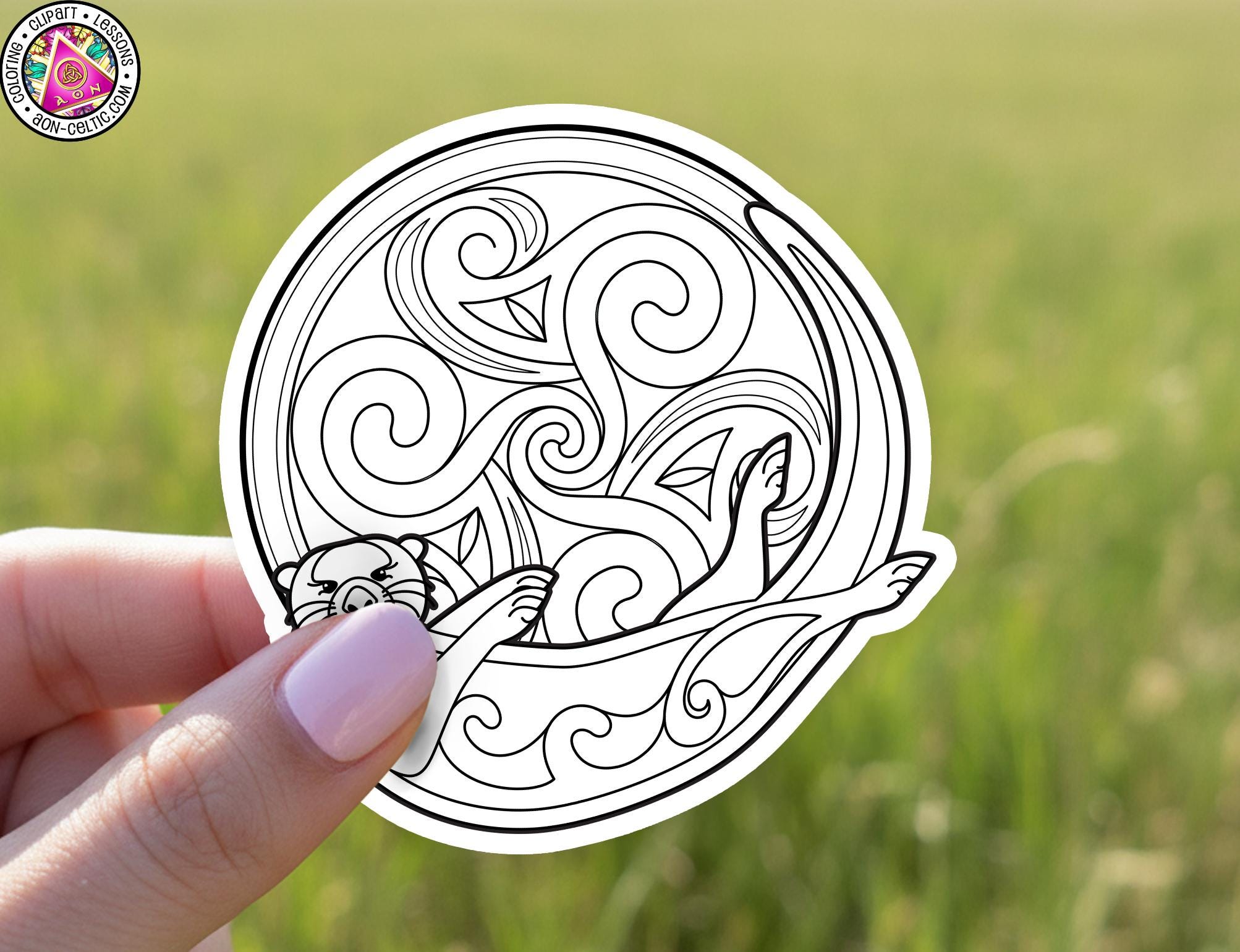 A hand holding a circular sticker with a black and white illustration of a cat.