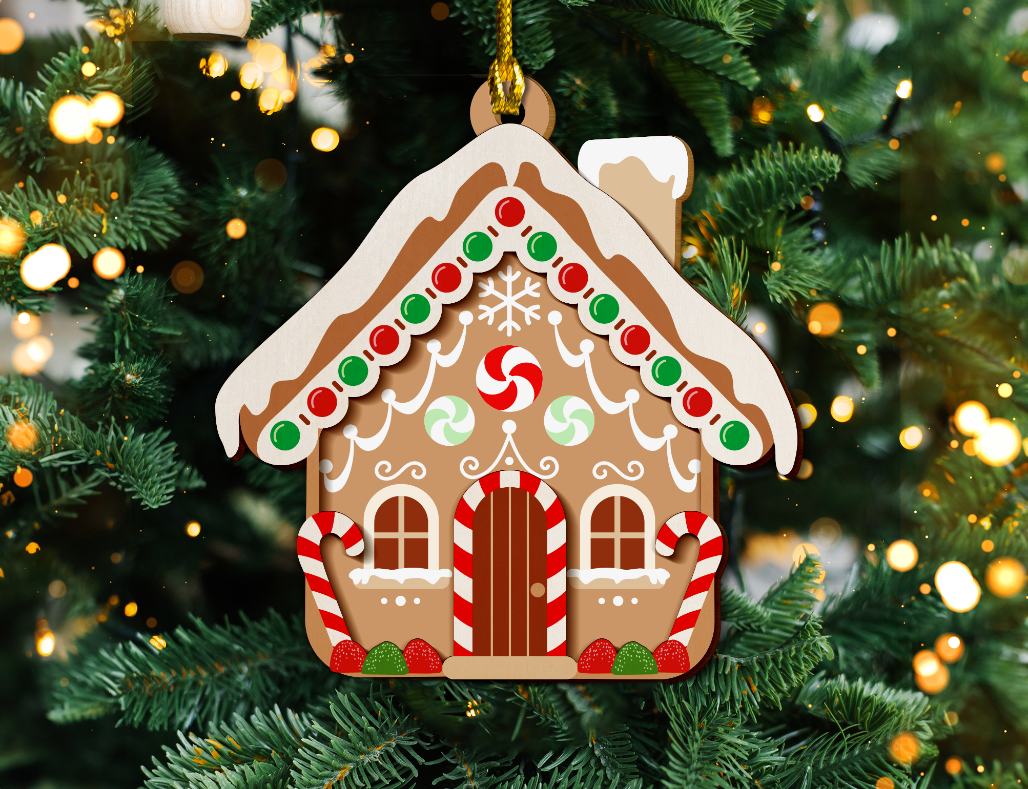 a gingerbread house ornament hanging from a christmas tree