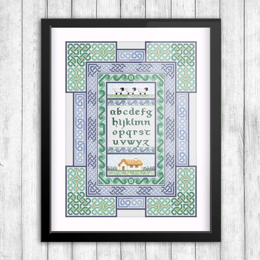 The image is a framed cross-stitch design featuring a pattern of letters and a house.