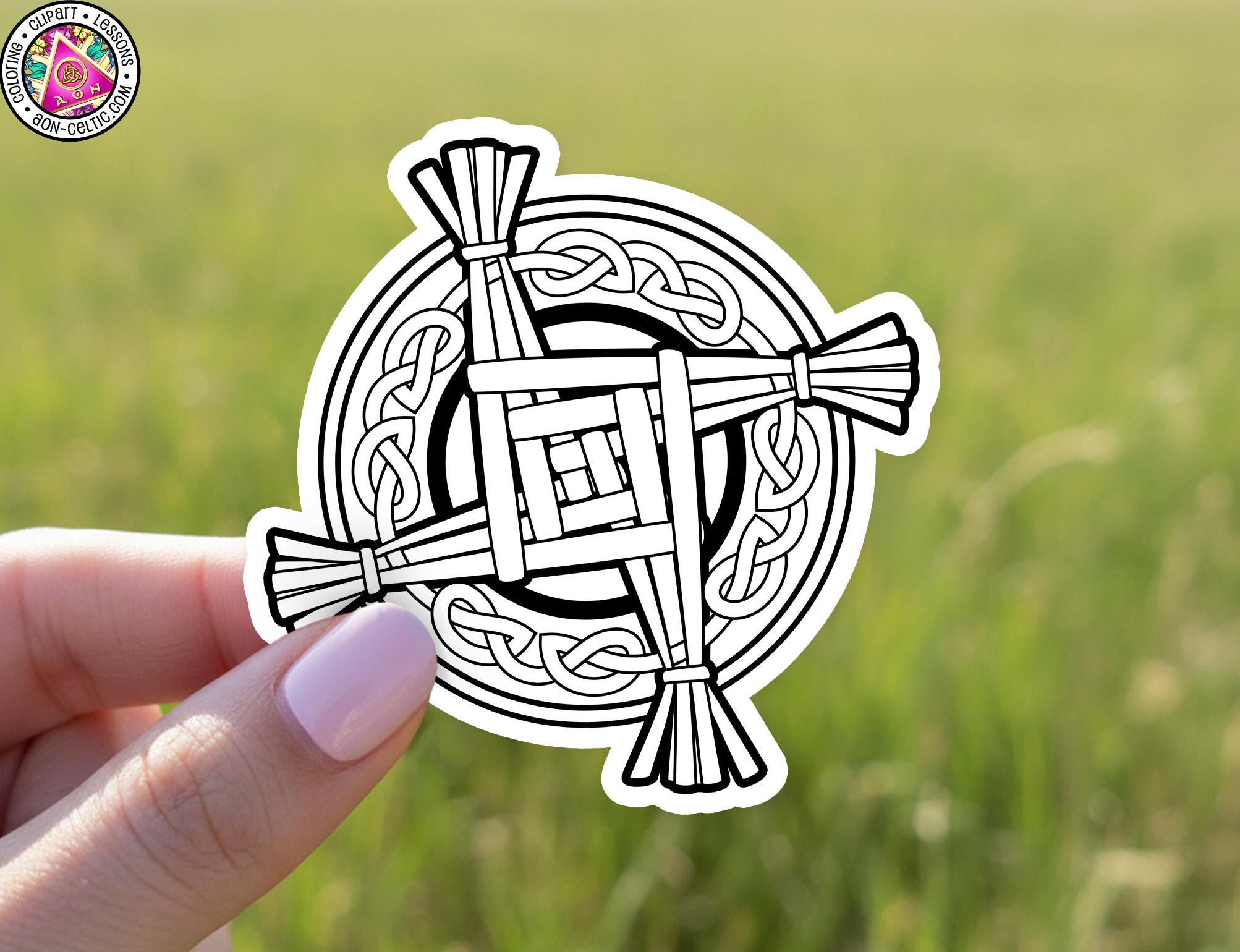 A hand holding a sticker with a circular design featuring a cross and a craid pattern.