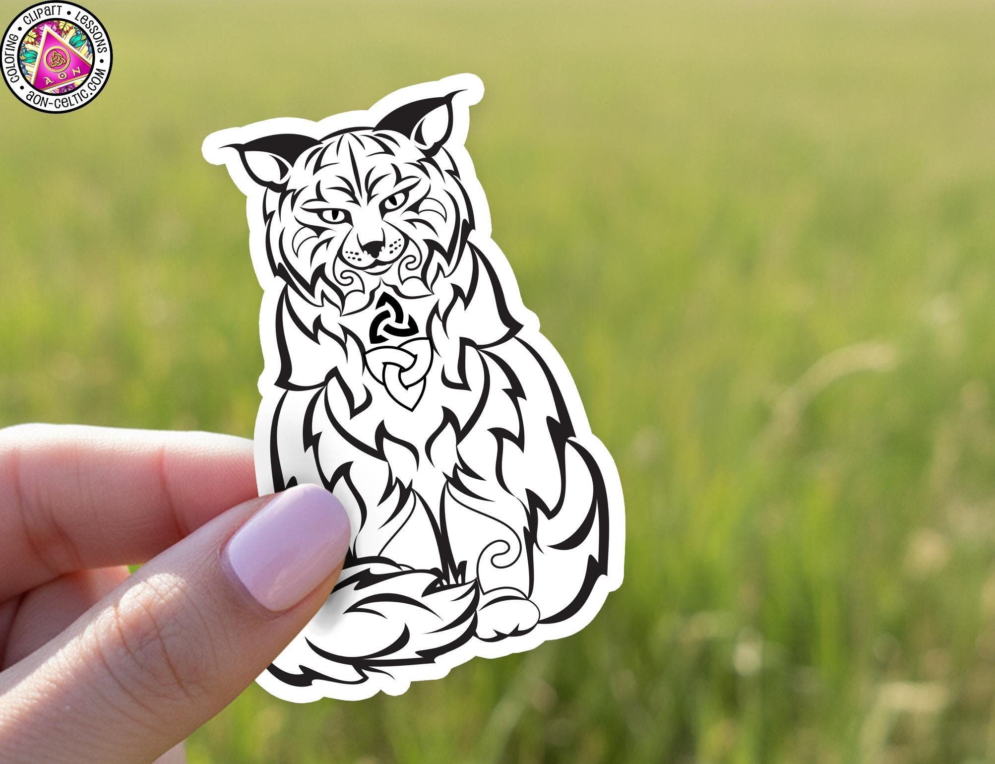 A hand holding a sticker of a stylized black and white tiger.