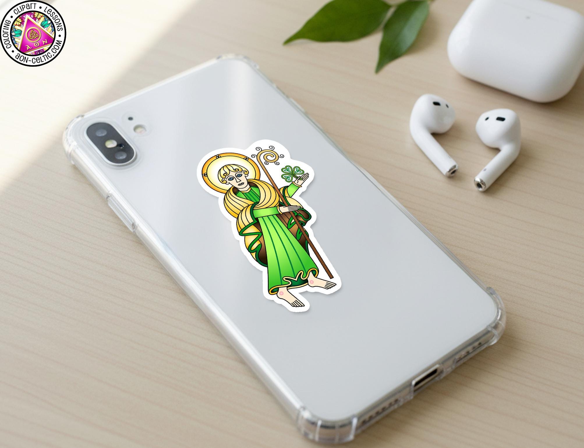 a smartphone with a sticker of a saint on it, along with a pair of earbuds and a white phone case.