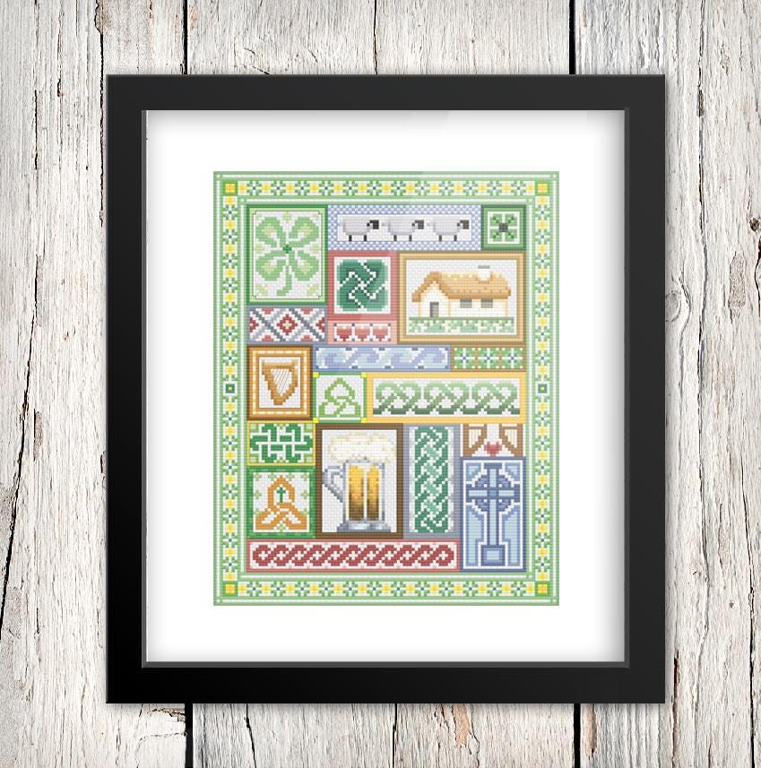 The image is a framed cross-stitch design featuring various patterns and symbols, including a house, a cross, and other geometric and floral elements.