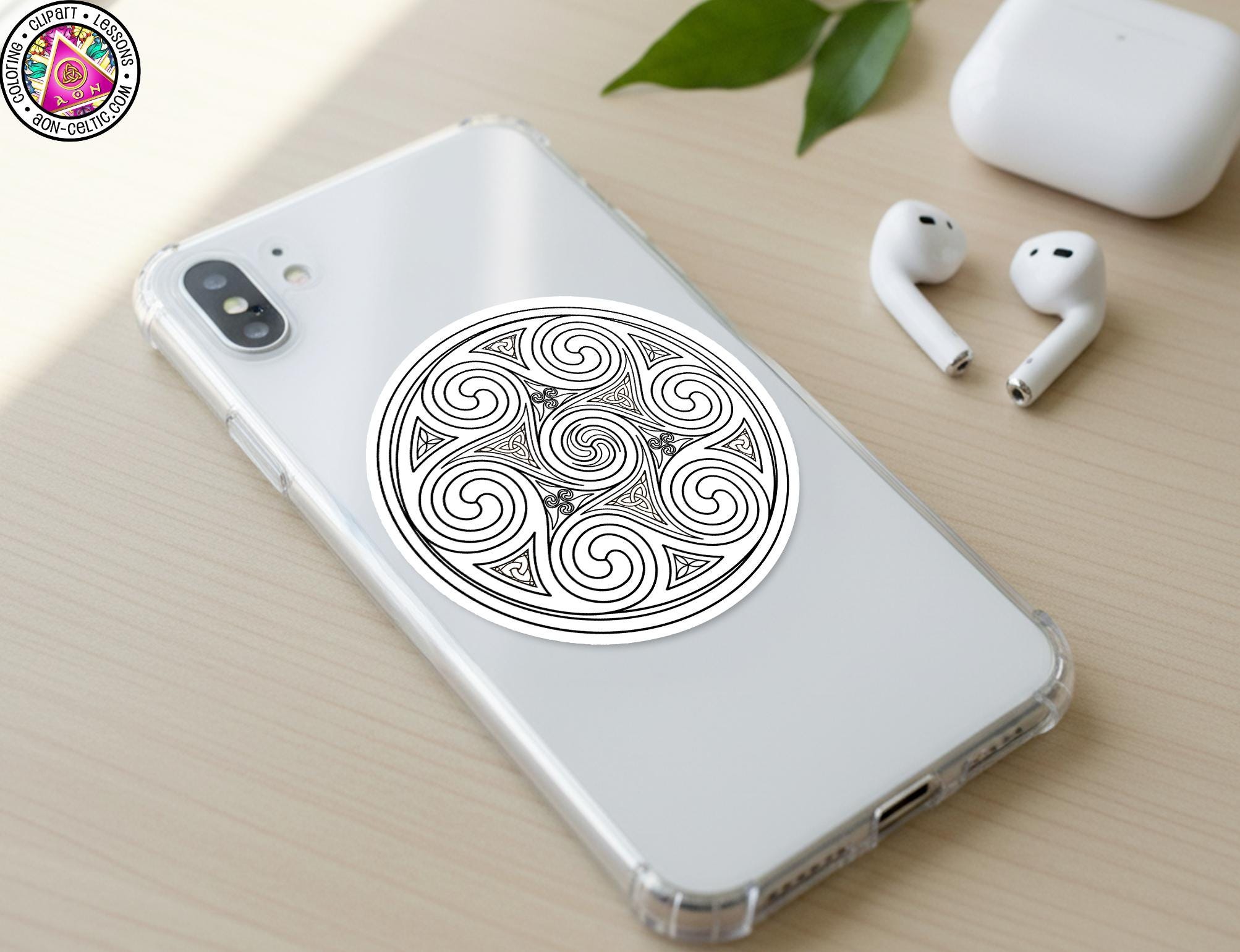 a smartphone with a decorative sticker on the back cover, along with a pair of earbuds and a white earbud case on a wooden surface.