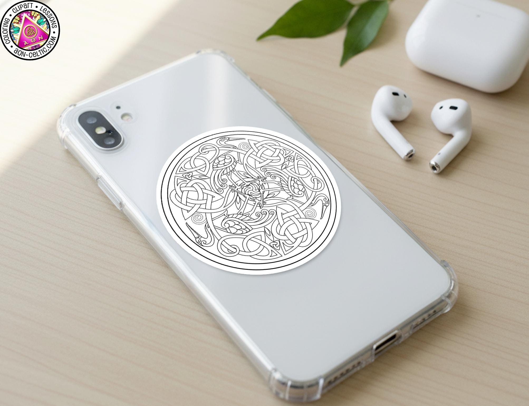 a smartphone with a sticker on the back cover, along with a pair of earbuds and a white earbud case on a wooden surface.
