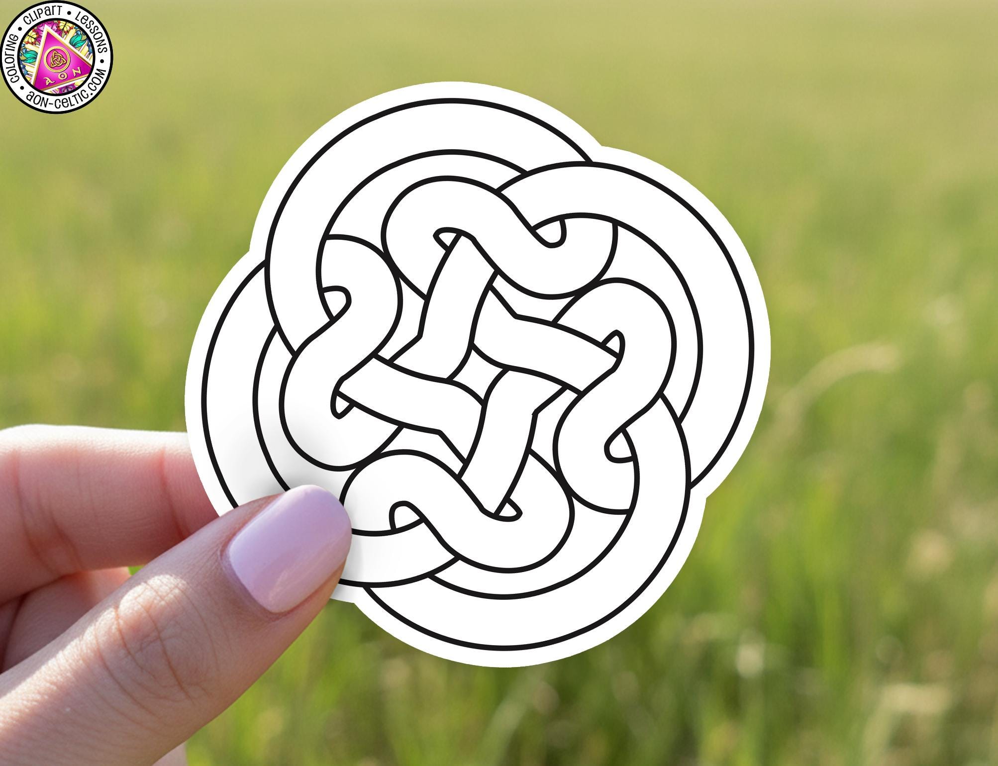 A hand holding a white sticker with a black and white design of a circular pattern.