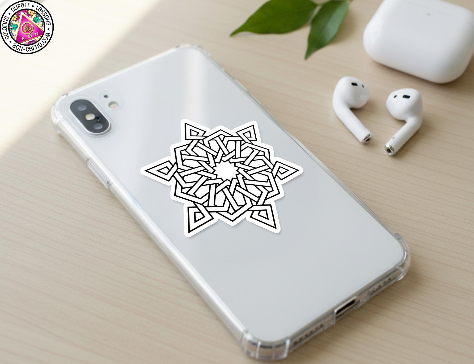 a smartphone with a sticker of a geometric design on its back cover, along with a pair of white earbuds and a white charging cable on a wooden surface.