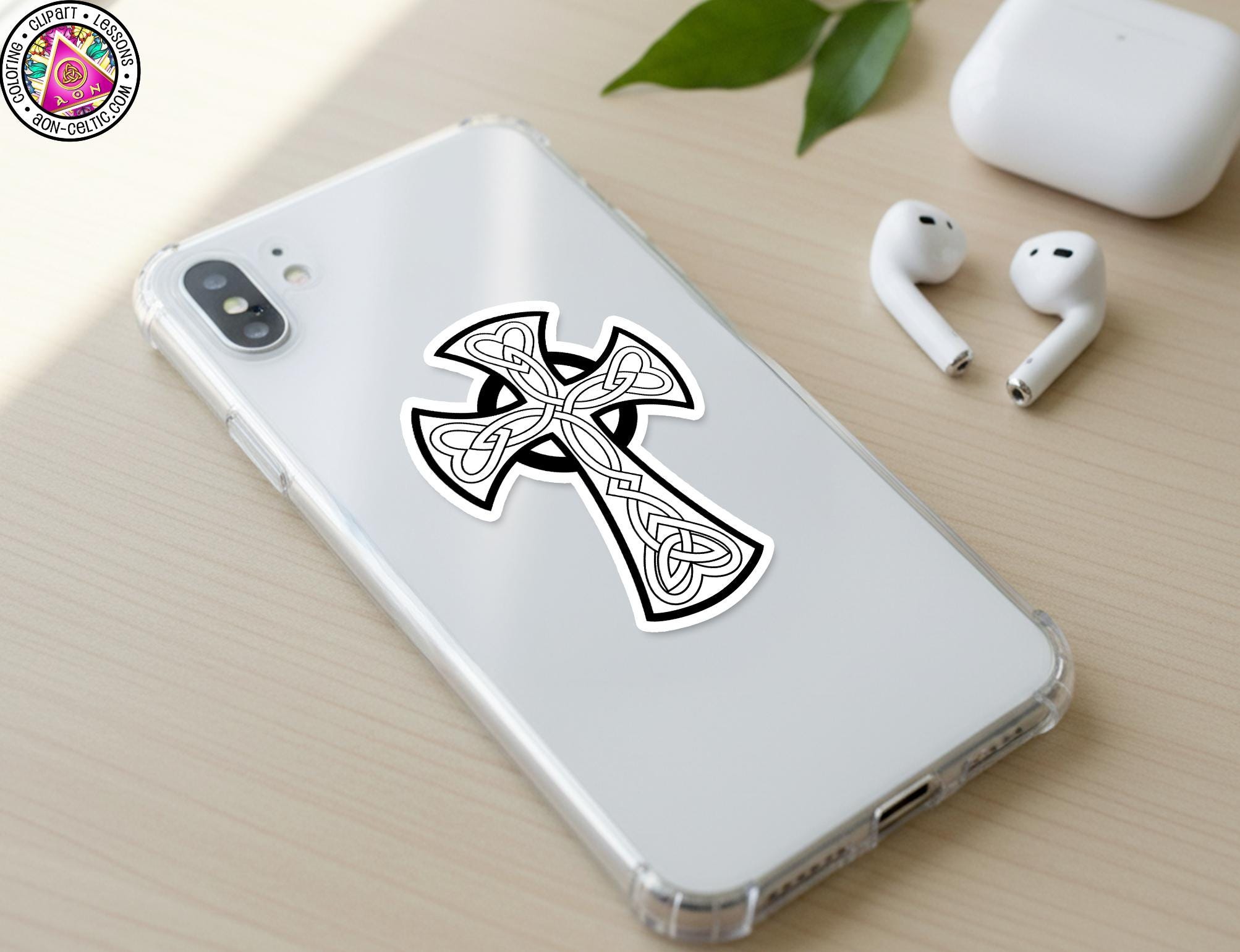 a smartphone with a sticker of a cross on its back cover, along with a pair of earbuds and a white earbud case on a wooden surface.