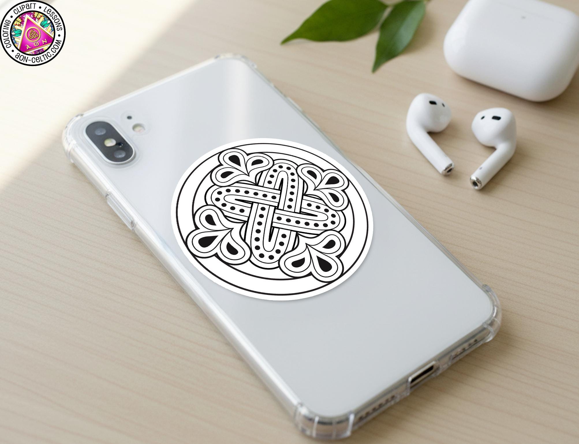 a smartphone with a sticker on the back cover, along with a pair of earbuds and a white earbud case on a wooden surface.