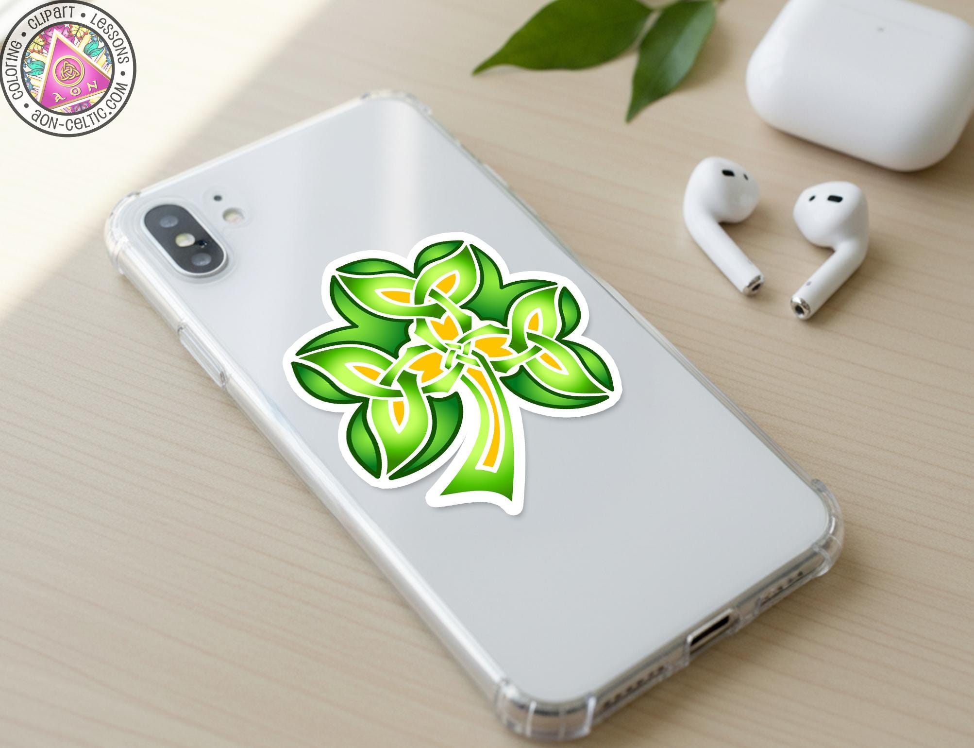 a smartphone with a green and yellow clover sticker on the back cover, along with a pair of white earbuds and a white phone case.