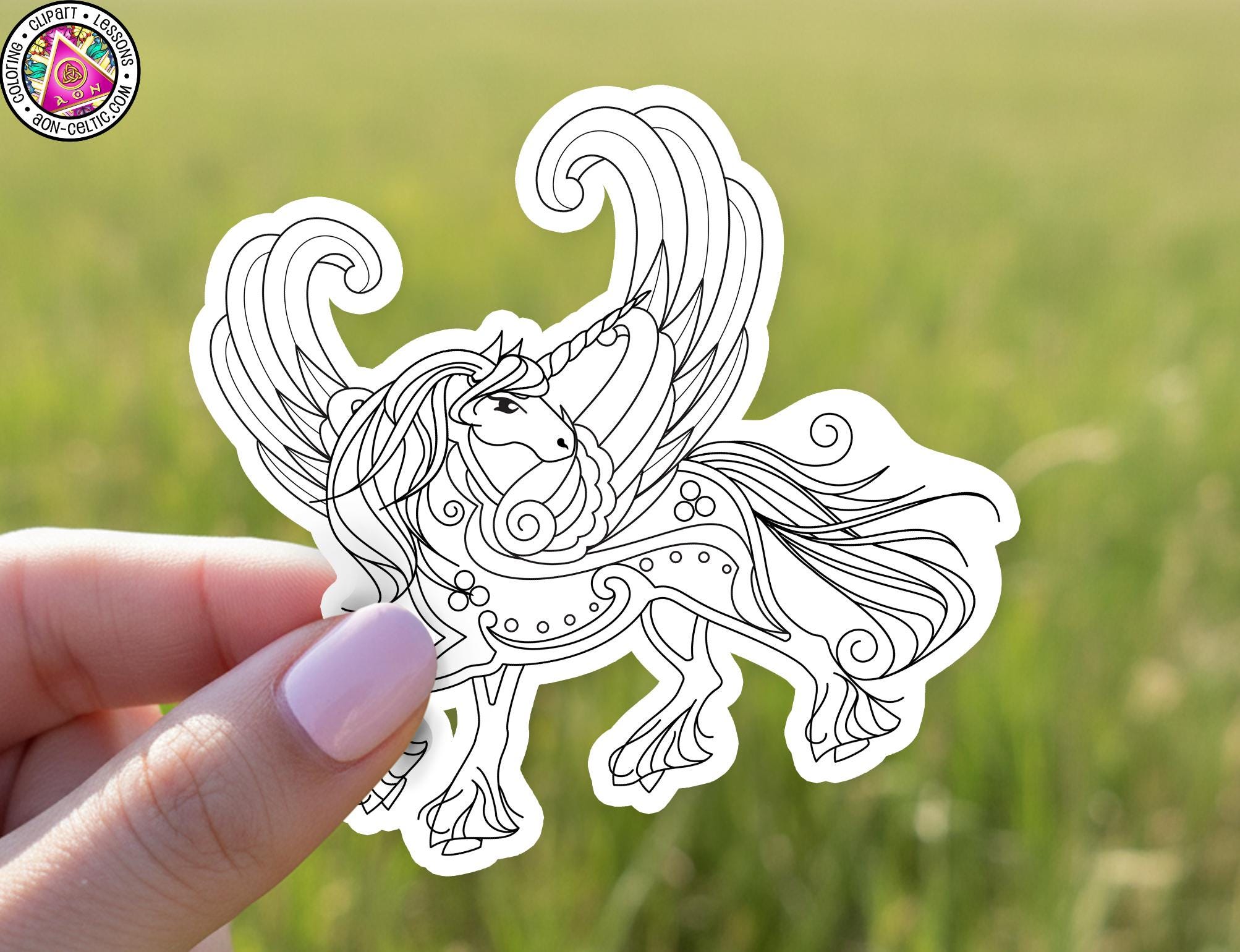 A hand holding a sticker of a stylized unicorn with wings and a flowing mane.