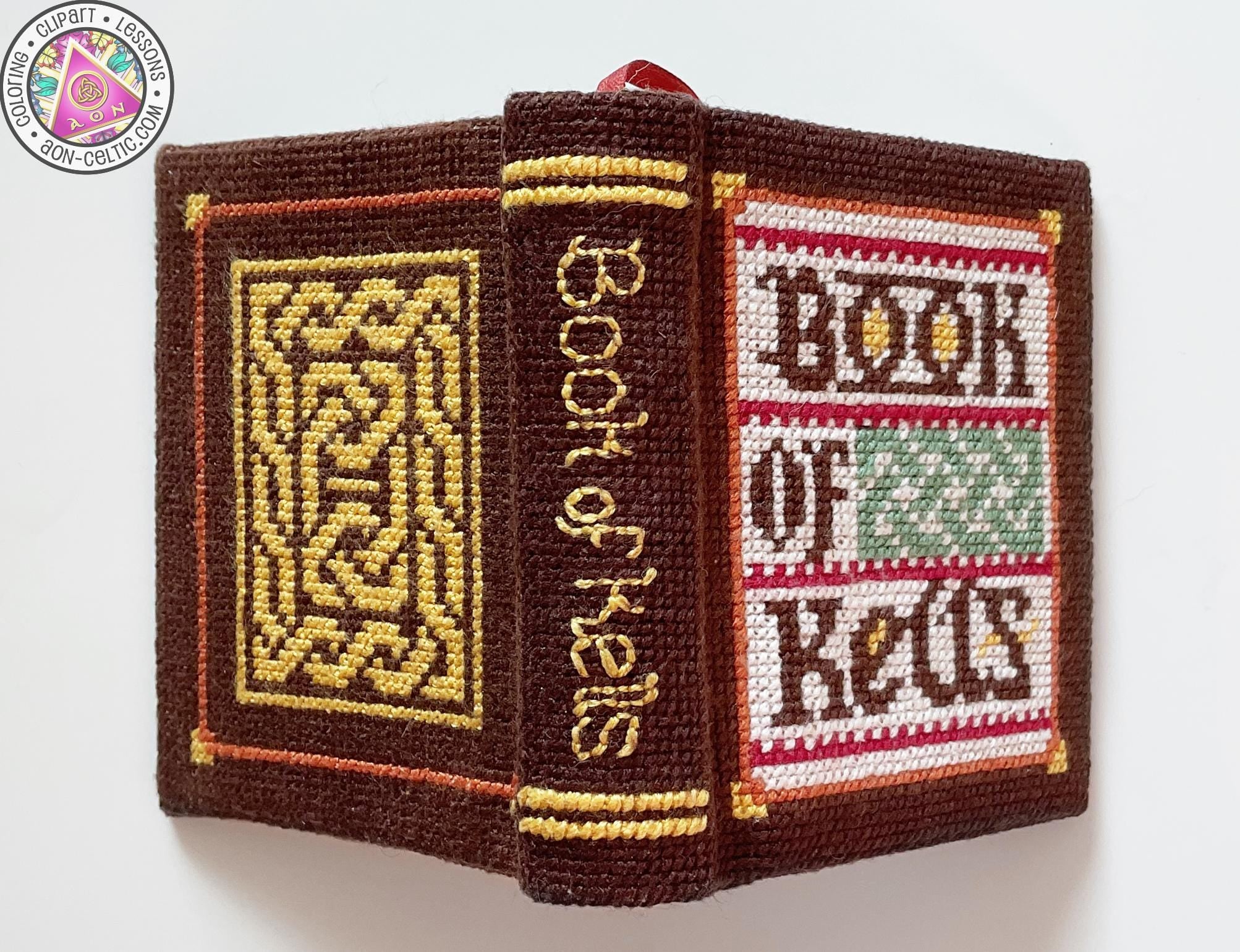 a book titled "Book of Kells" with intricate embroidered designs on the cover and spine.