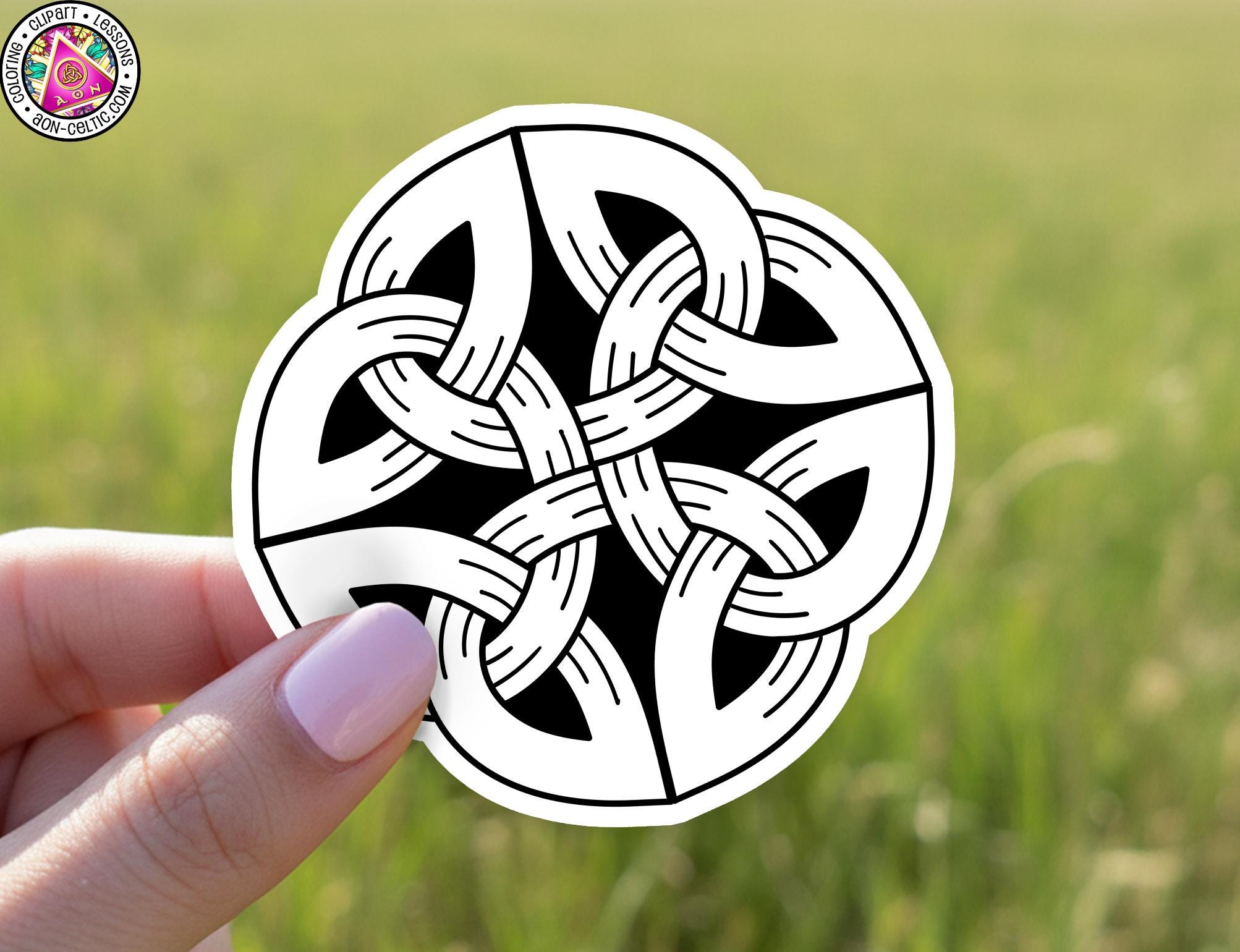 A hand holding a sticker with a black and white design featuring a circular pattern resembling a flower or a mandala-like shape.