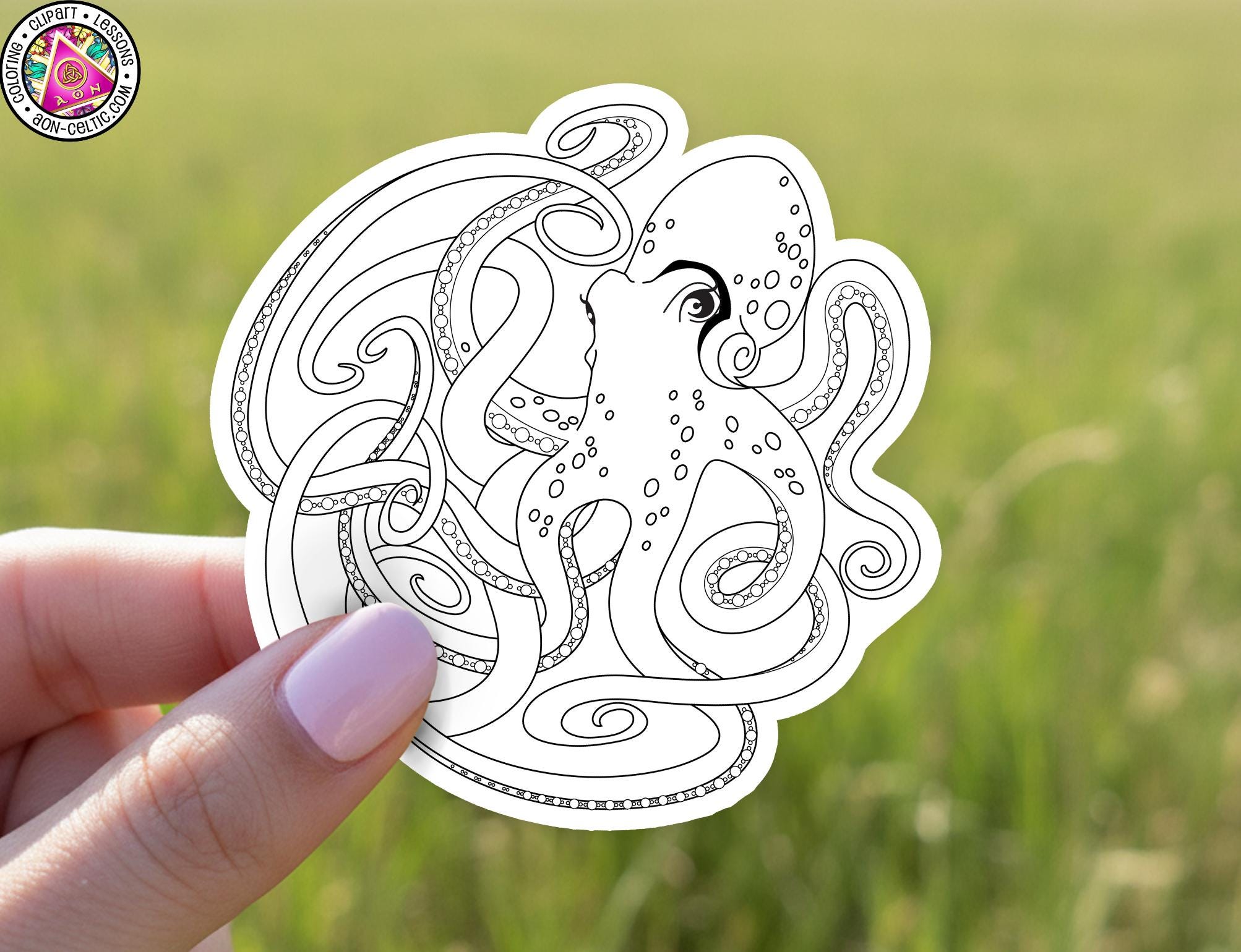 A hand holding a sticker featuring an intricate black and white illustration of an octopus with its tentacles spread out.