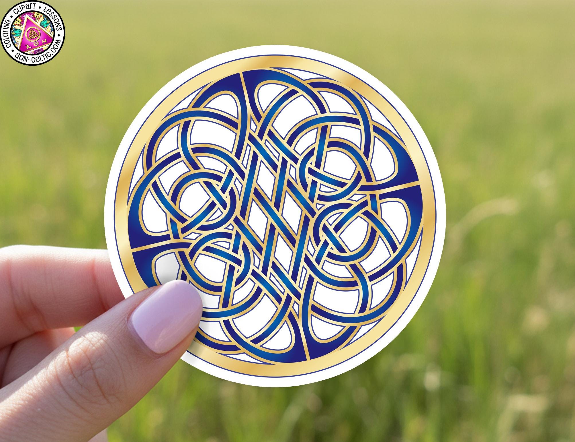 A hand holding a circular sticker with a blue and gold Celtic knot design.