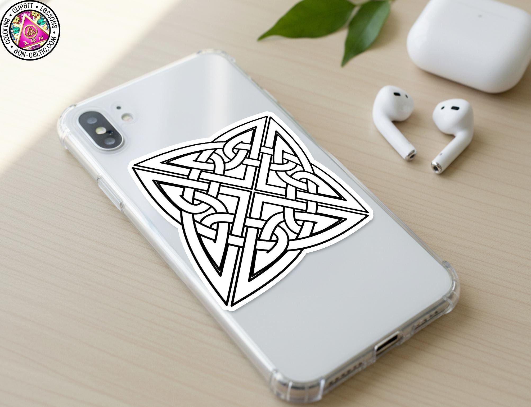 a smartphone with a sticker of a Celtic knot design on its back cover, along with a pair of white earbuds and a white charging cable on a wooden surface.