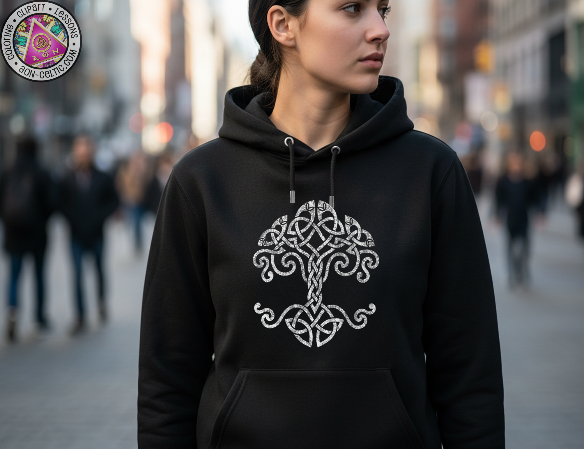A woman wearing a black hoodie with a white tree design stands in a city street, surrounded by other people.