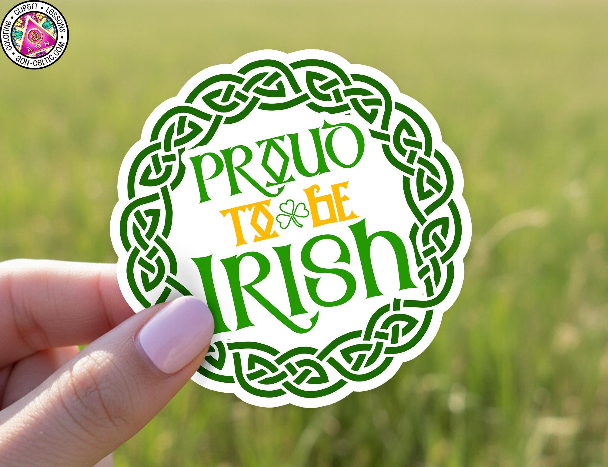 A hand holding a sticker with the text "PROUD TO BE IRISH" in a circular design with a Celtic knot pattern.