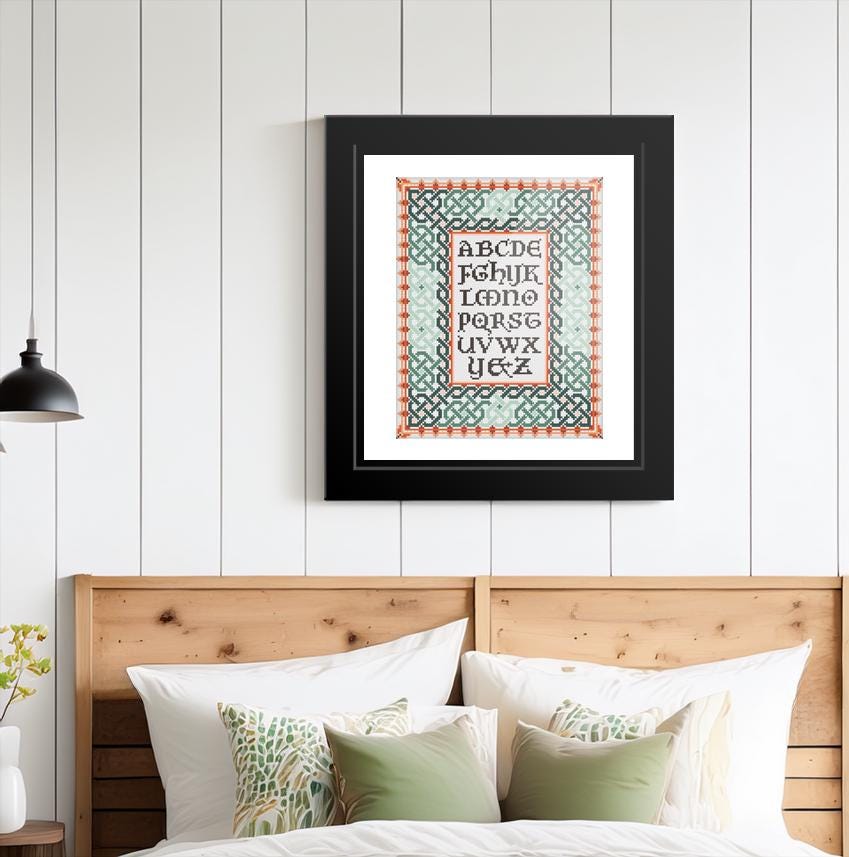 a framed print of the alphabet hanging on a wall above a bed with wooden headboard.