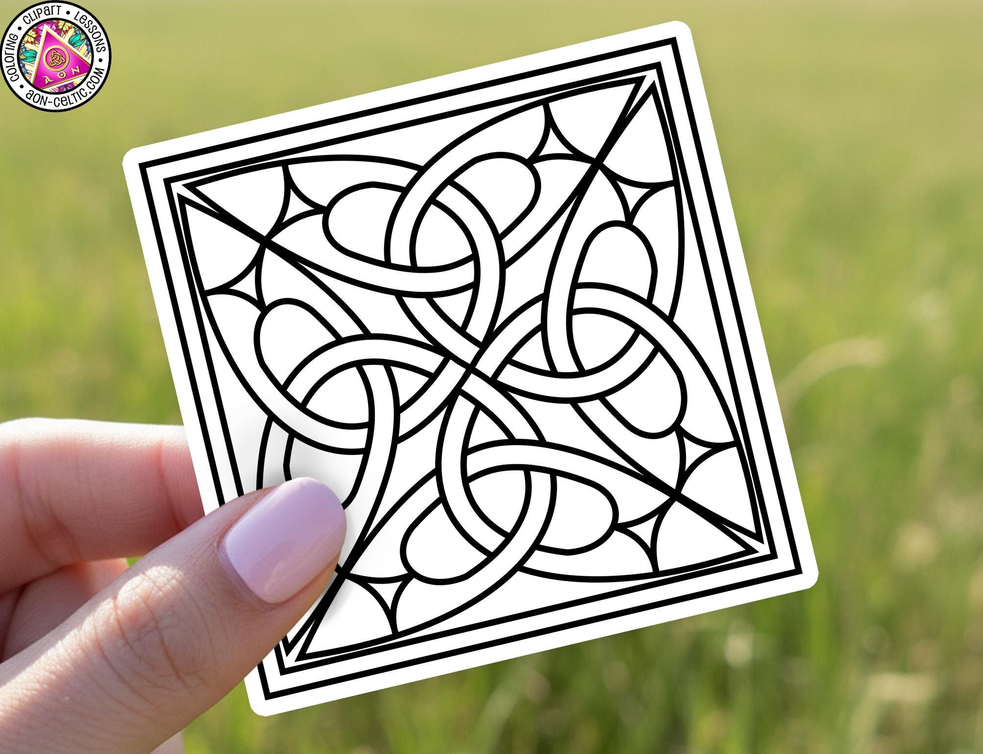 A hand holding a sticker with a black and white geometric design featuring interlocking shapes and lines.
