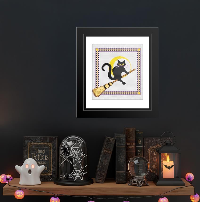 a shelf with various Halloween-themed items, including a framed picture of a black cat on a broom, a spider web decoration, a lantern, and a crystal ball.