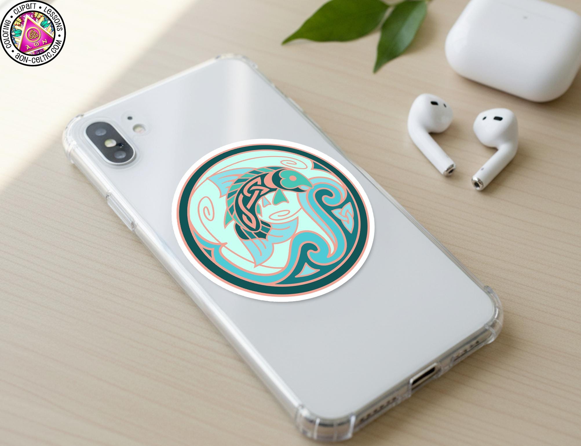 a smartphone with a sticker on the back cover, along with a pair of earbuds and a white earbud case on a wooden surface.